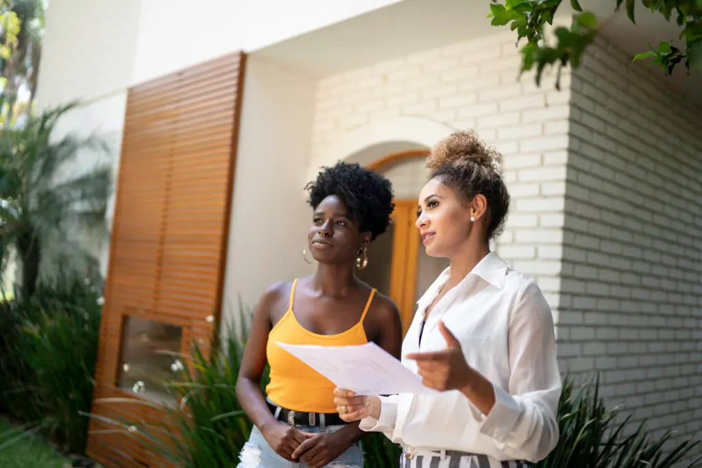 Real estate agent/financial advisor talking to a client in front of a house
