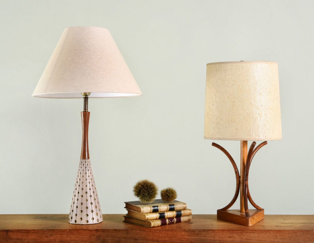 Books on wooden shelf between two vintage house lights with classic style lamp shades