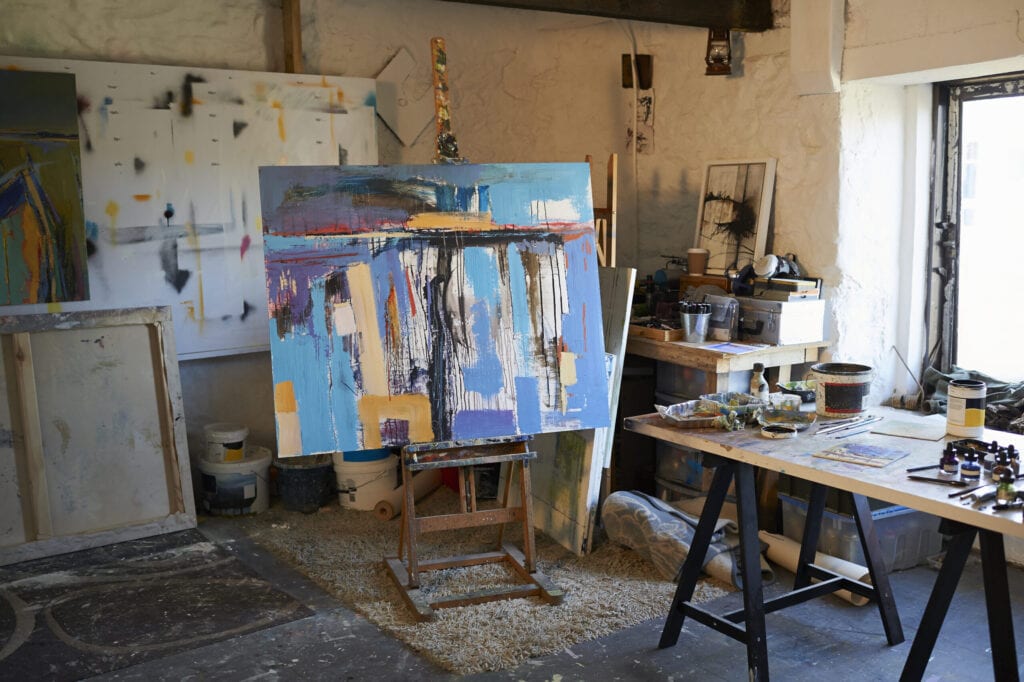 A large canvas painting on an easel in a creative artist studio.
