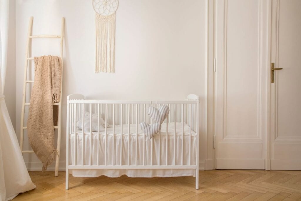 Nursery with neutral colors and heart-shaped pillows hanging from crib