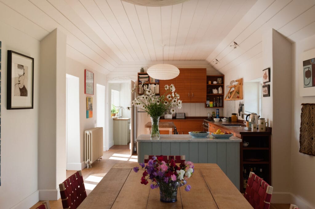 Open plan kitchen dining room. The Arts & Crafts dining table is oak and the chairs are by Alvar Aalto. The marble topped work station is painted in Light Blue Estate Eggshell by Farrow and Ball and the cupboards are teak.