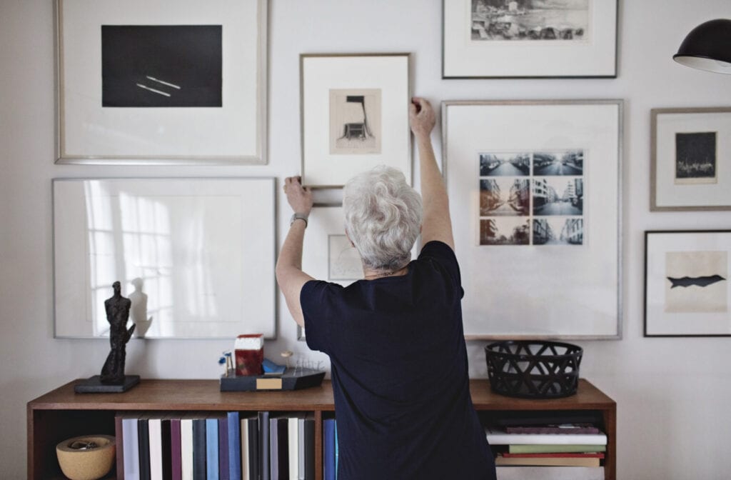 Woman hanging pictures on the wall, grey, beige, black, and white interior design