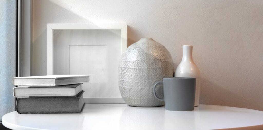 Ceramic vases and mock up frame on white table in minimal workspace next to the windows
