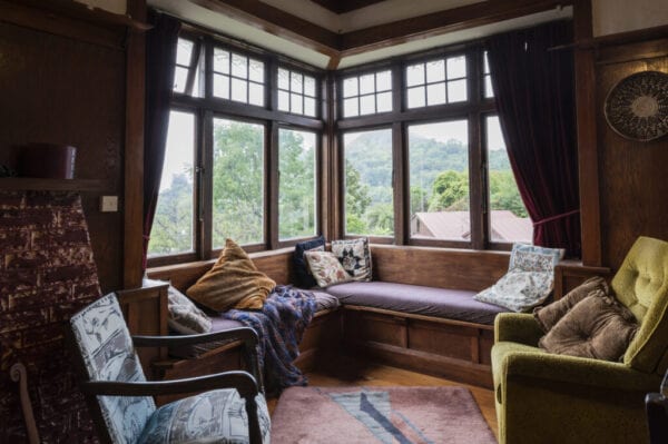 Living room in 1920s bungalow with vintage furniture and view to surrounding woodland