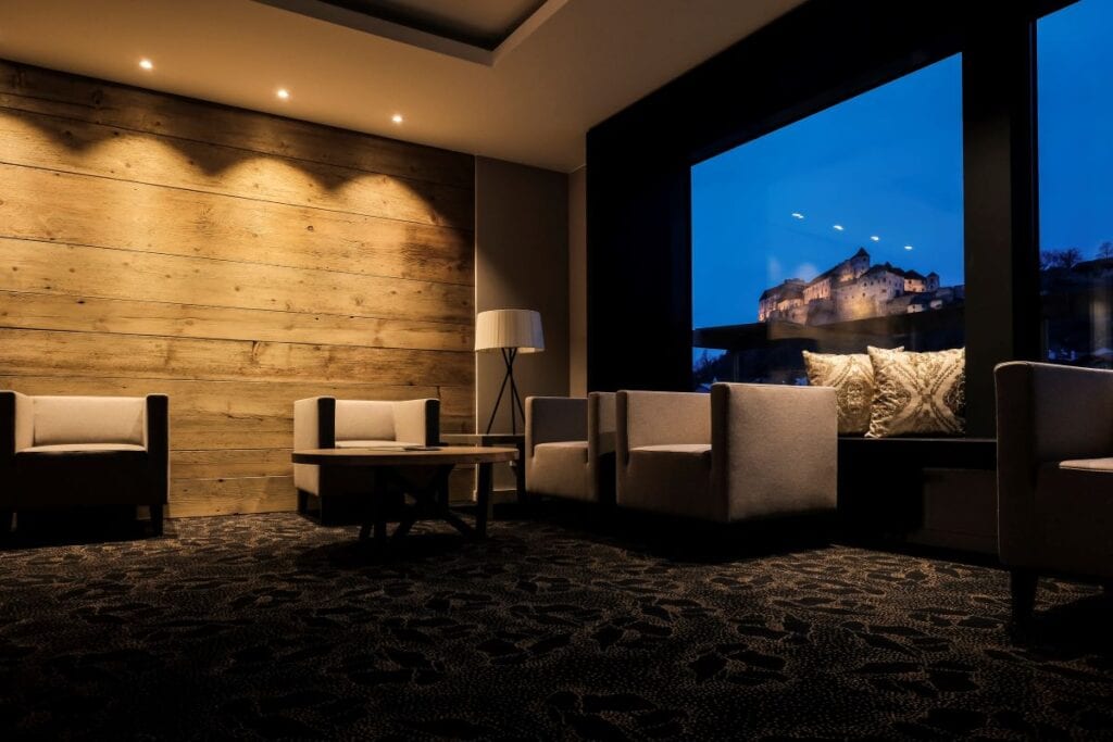 Living room has wood wall and view of castle at night