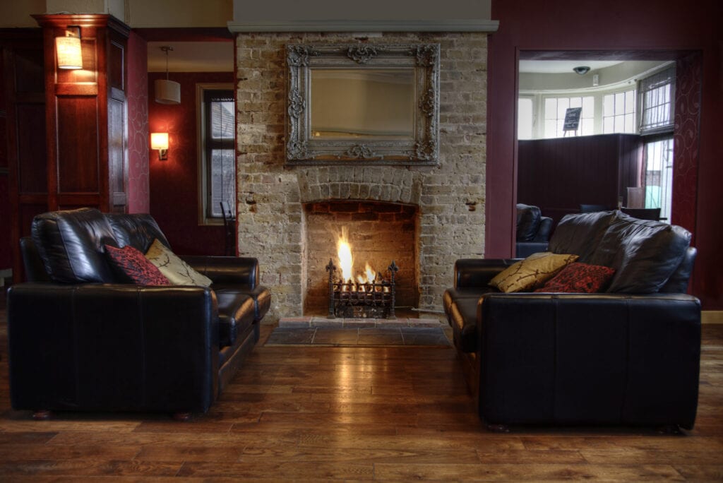 Room with leather sofas and an open fireplace.