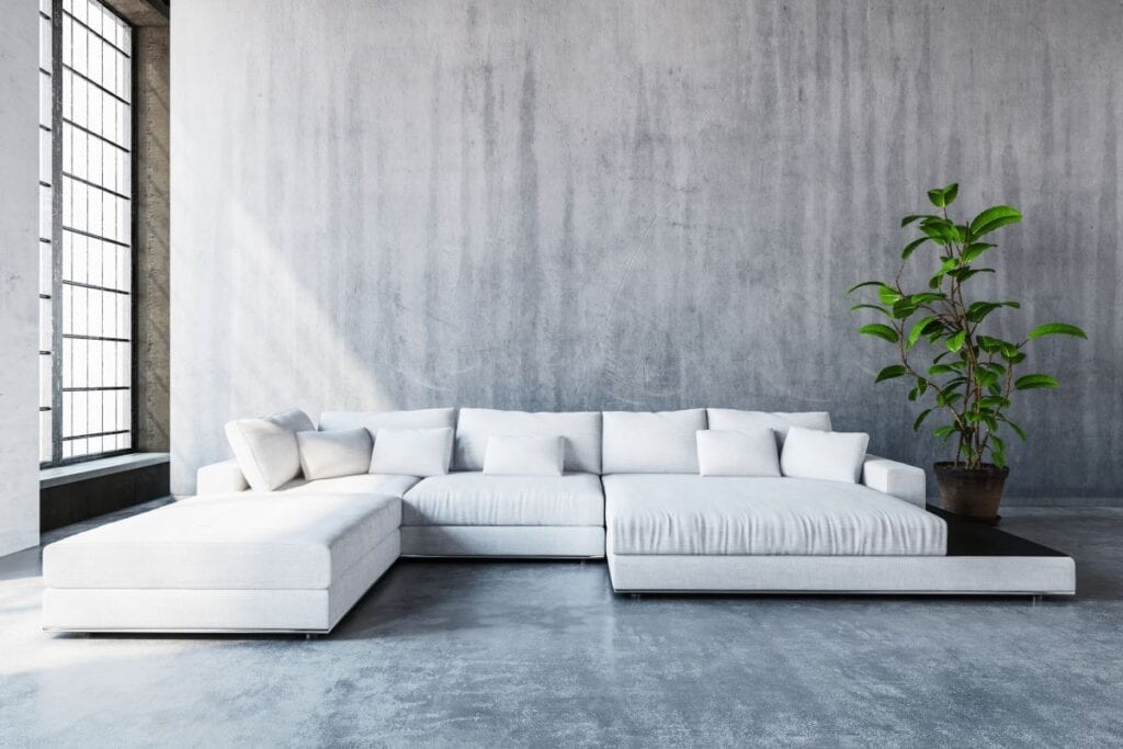 Modern white sofa in industrial living room with concrete walls and floors