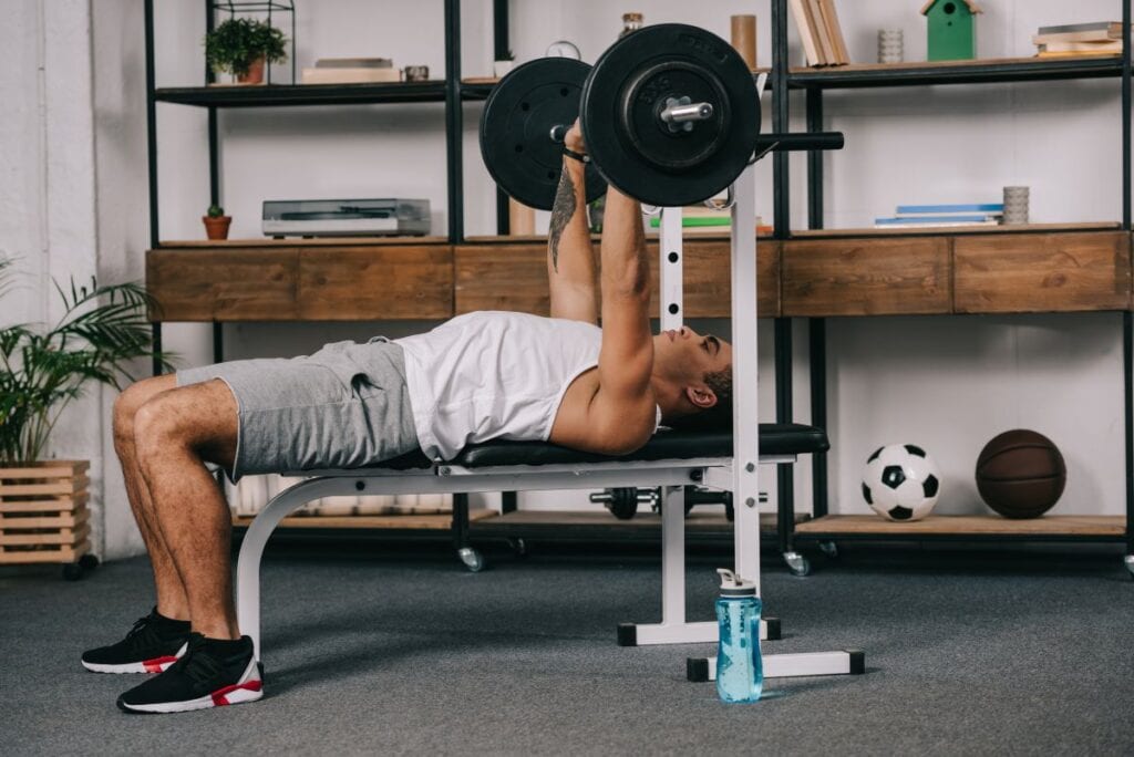 Man lifting weights in home gym with rubber flooring