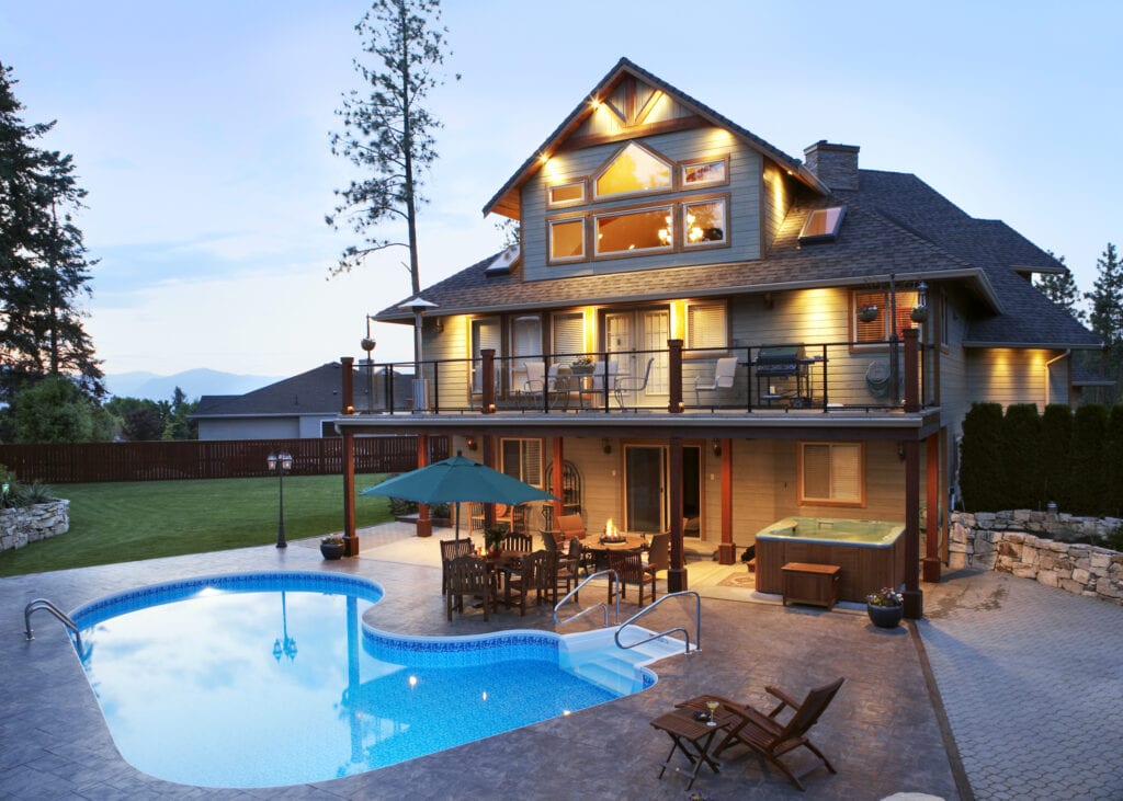 Canada, British Columbia, Kelowna, Exterior of large illuminated house by swimming pool at dusk