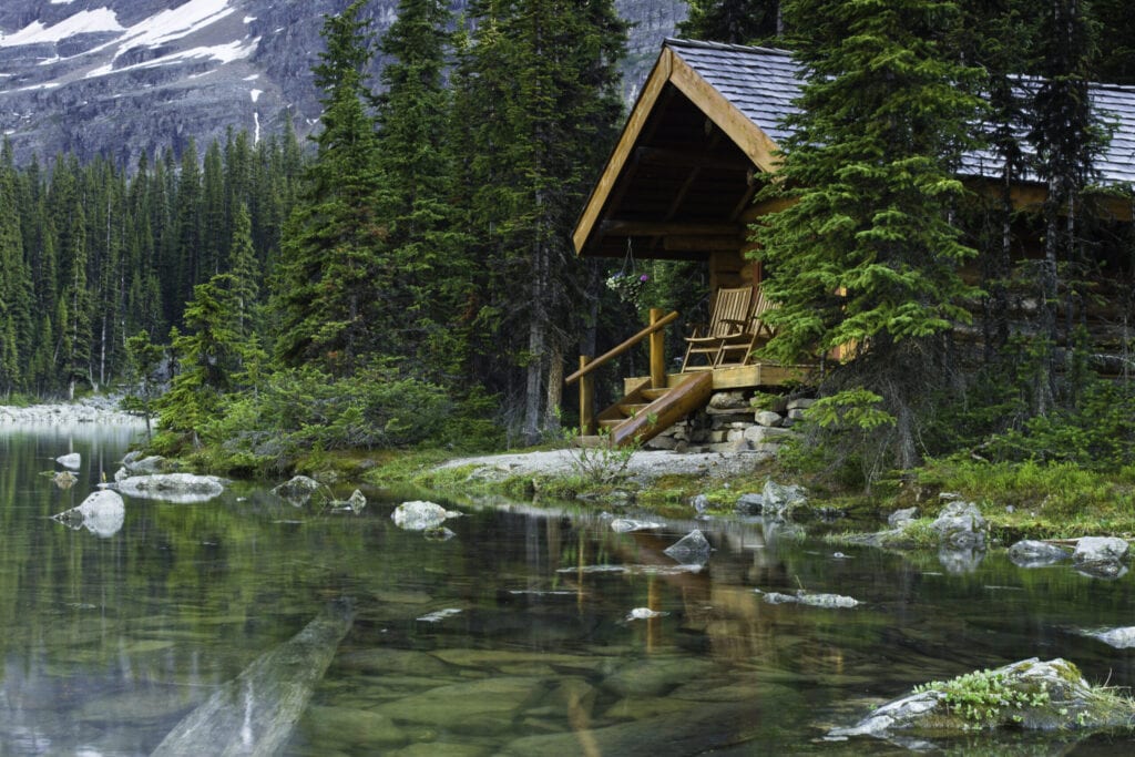 Evening shot of a log cabin at Lake O'Hara, BC, Canada. Rocks are seen beneath the water surface.  Beautiful scenic vacation get away.