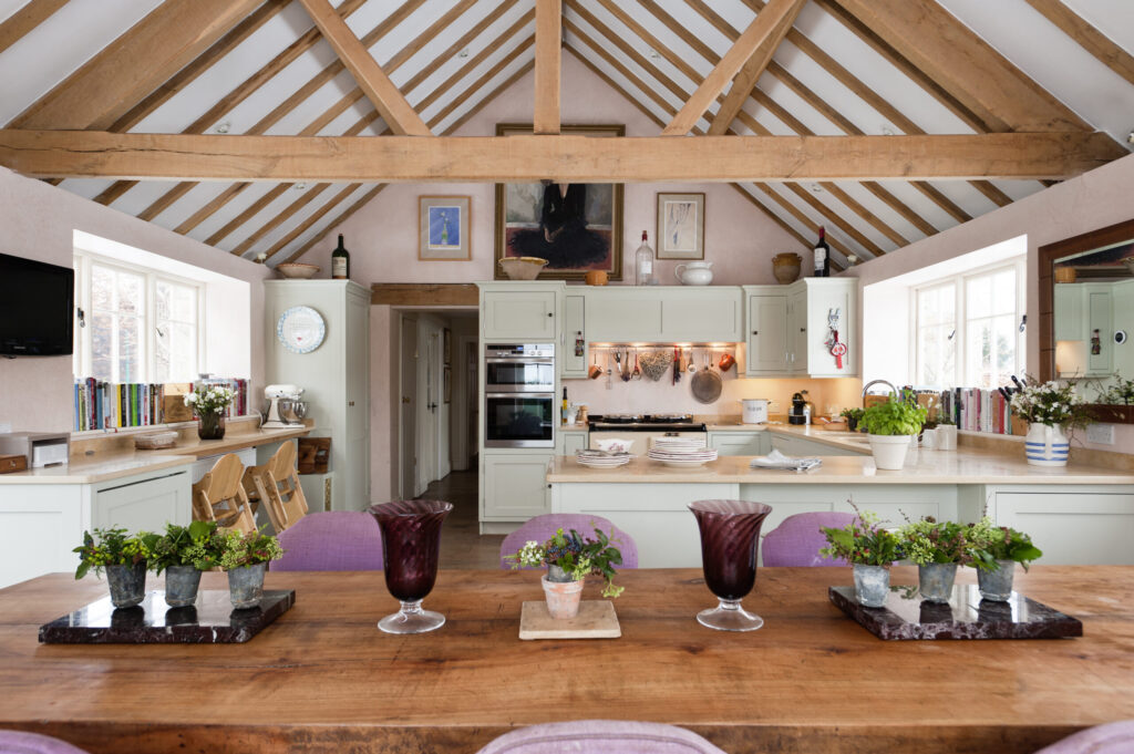Open plan kitchen diner with pitched ceiling and beams. The kitchen units were made by Kevin Anderson and painted in Dulux Gooseberry