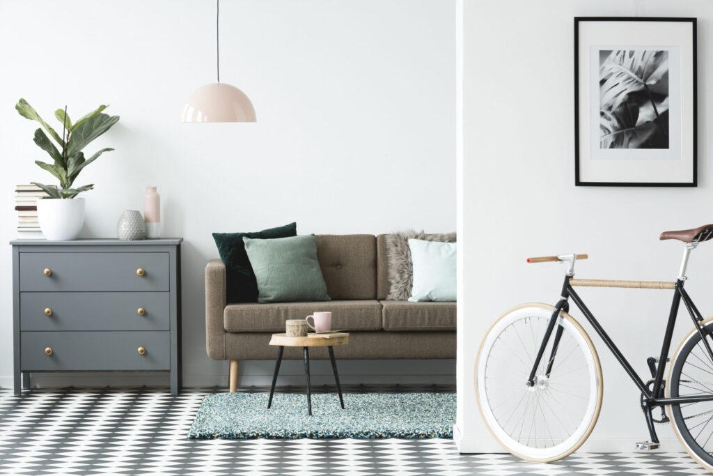 Bicycle and poster in cozy living room interior with wooden table near brown couch and grey cabinet