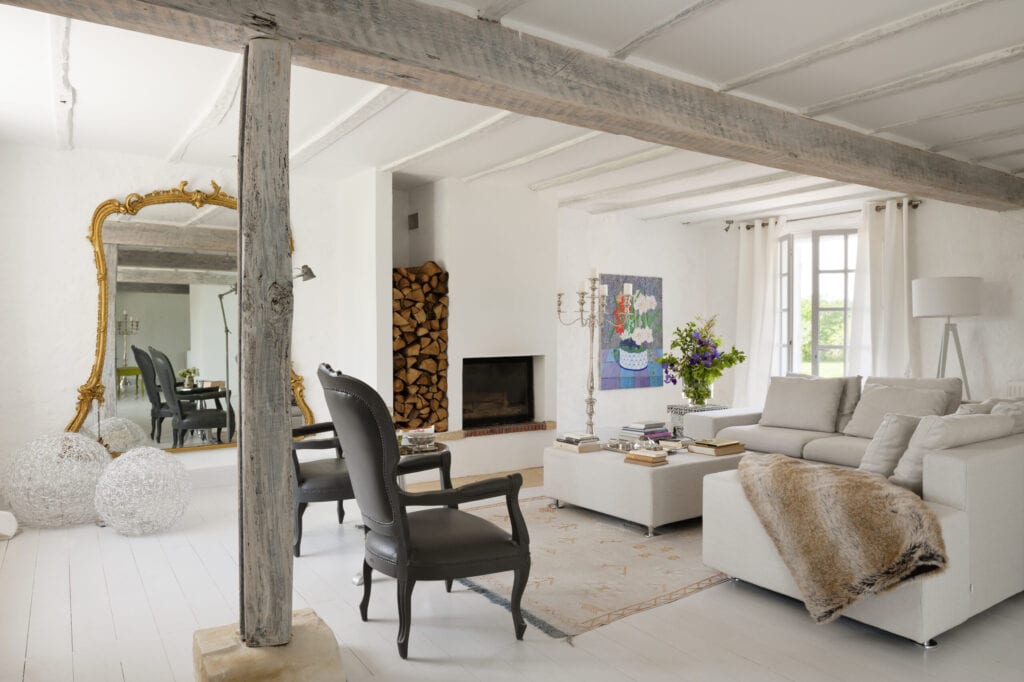 Pair of Louis XV armchairs designed by Pieter Jamart in white open plan living space with oversized gilt framed mirror and sofas