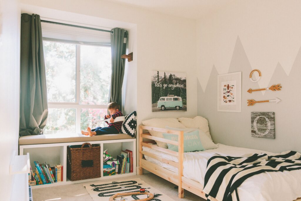 Boys room decor, young boy sitting in window of his bedroom