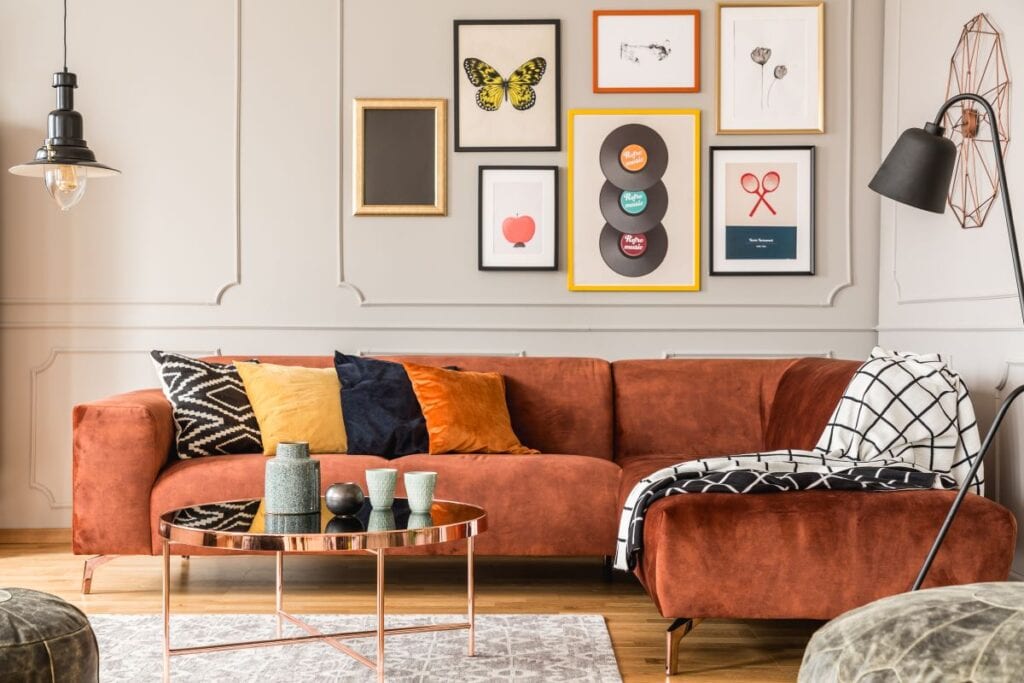 Eclectic living room with orange velvet sectional and mirror table