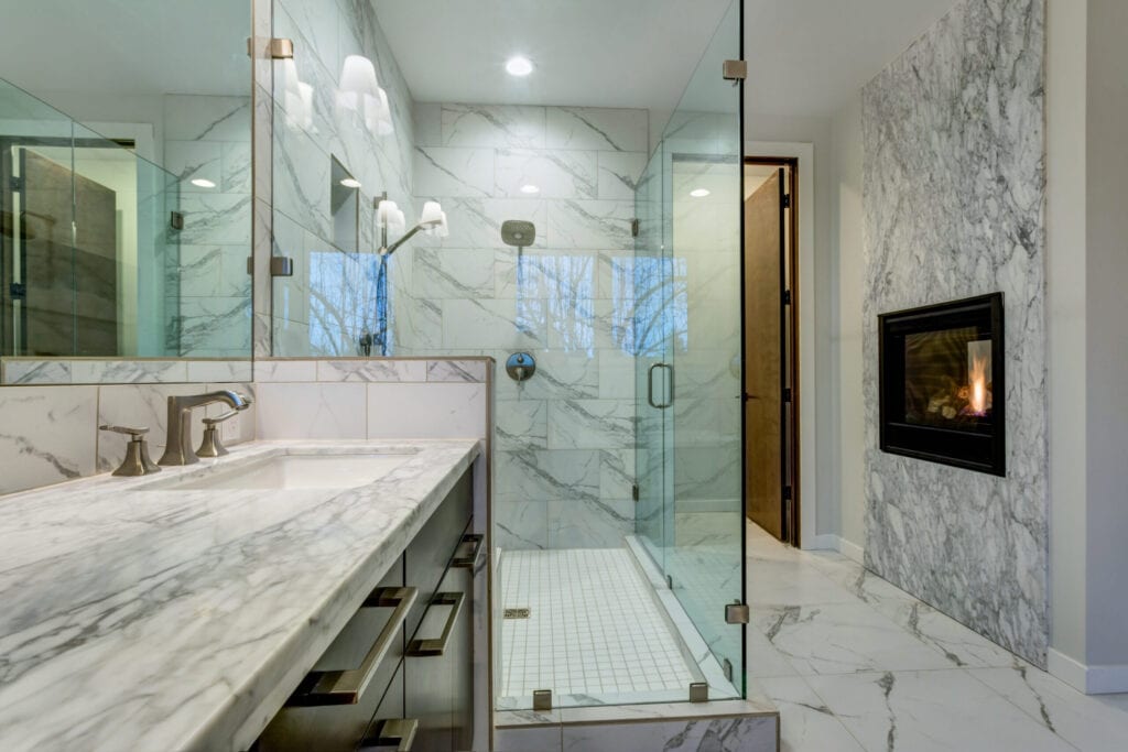 Incredible master bathroom with fireplace, Carrara marble tile surround, modern glass walk in shower, espresso dual vanity cabinet and a freestanding bathtub.
