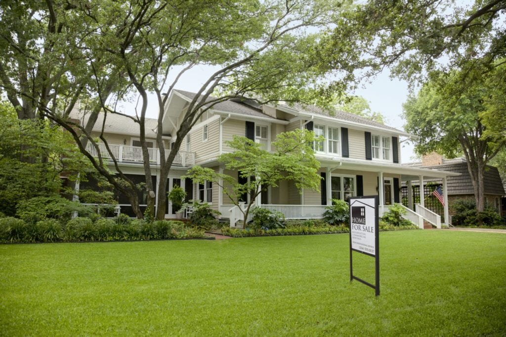 view of residential home with for sale sign on the large green front lawn