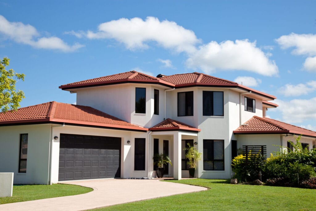 "Close up of the front view of a new modern two story family home with clouds, blue sky, green grass and landscaped gardens. Click to see more..."