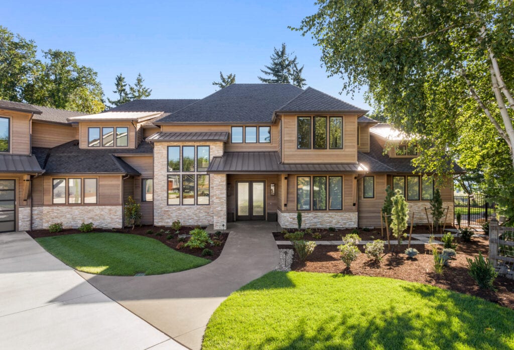 of home with manicured lawn, and backdrop of trees and blue sky