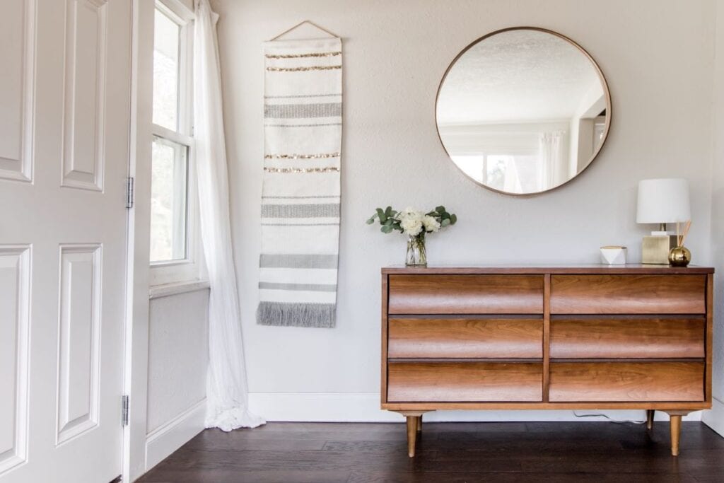 Foyer with wood console table, mirror, and wall tapestry