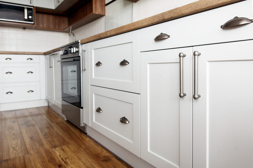 Close up of white kitchen cabinets with wood countertop and brass handles