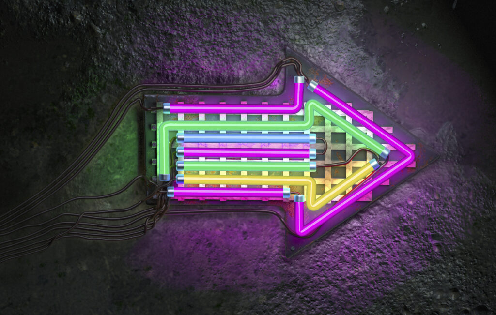 A neon multi coloured arrow points right on a textured wall