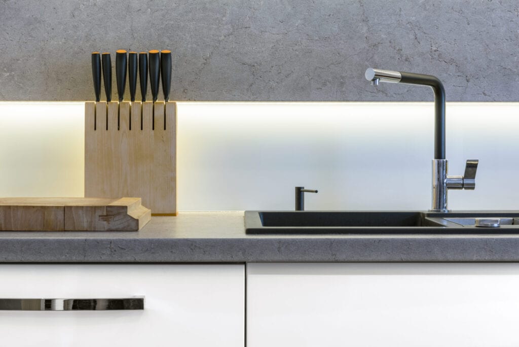 Detail of modern kitchen with knifes, sink and wooden cutting board