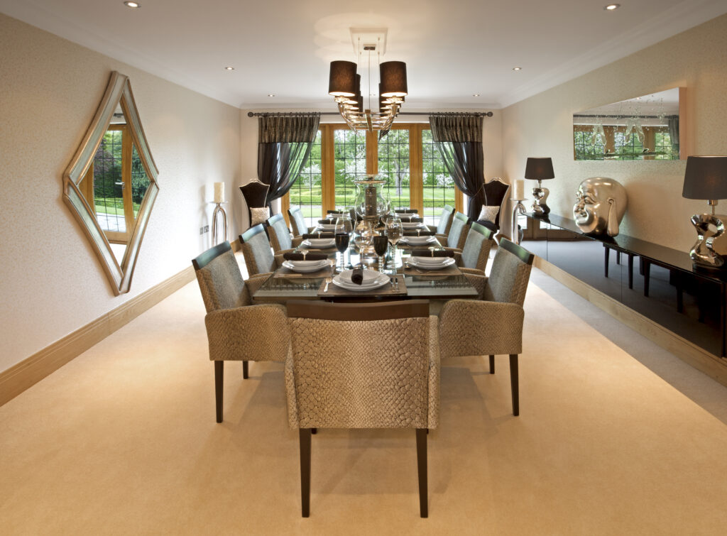 A large dining room in a luxury new home, tastefully decorated by a leading Interior Designer. A long eight-seat table has been set for lunch or dinner.