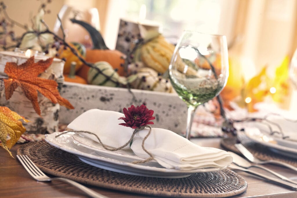 Autumn Thanksgiving holiday dining table place setting with a centerpiece of pumpkins and gourds