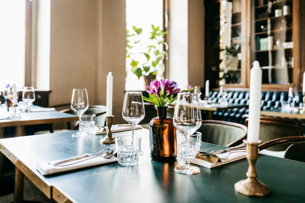 A restaurant table with wine glasses and candles, ready for customers to sit down for lunch.