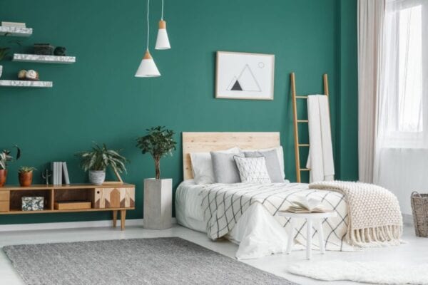 Modern bedroom with green walls and bed with wood headboard