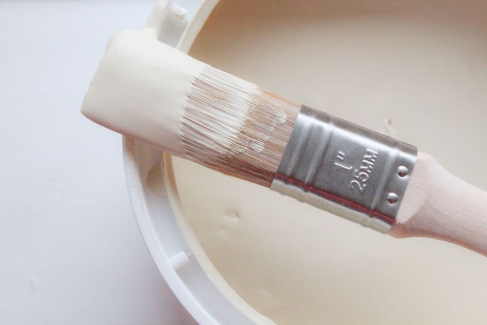 Close up of cream paint can and paintbrush