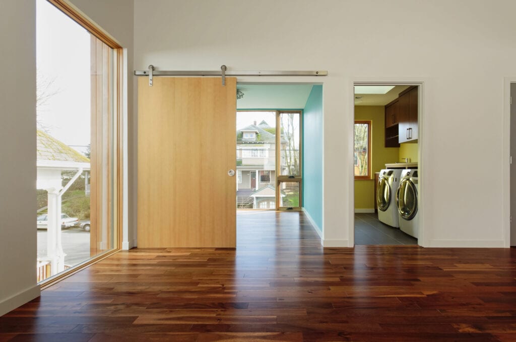 Modern home interior with View of upstairs laundry room and hardwood floors and barndoor style door.