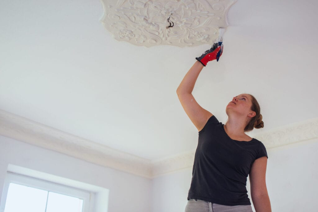 Woman repainting stucco in a house.