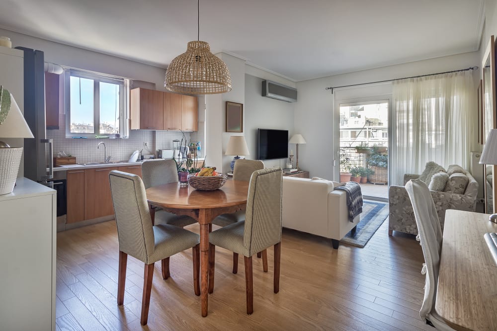 Open-concept of a kitchen, dining wooden table and living room with balcony in a very small apartments.