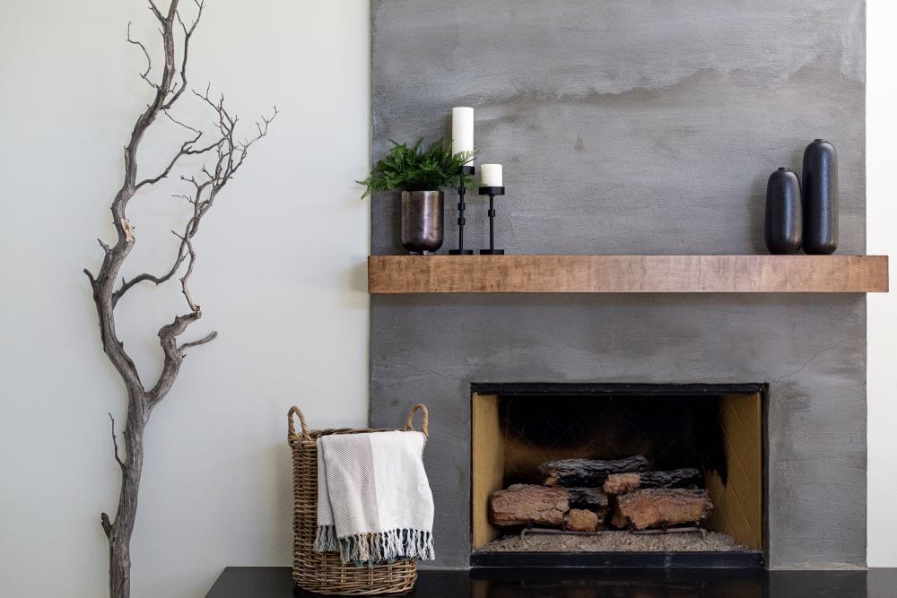 Plants and basket with throw blanket surrounding fireplace