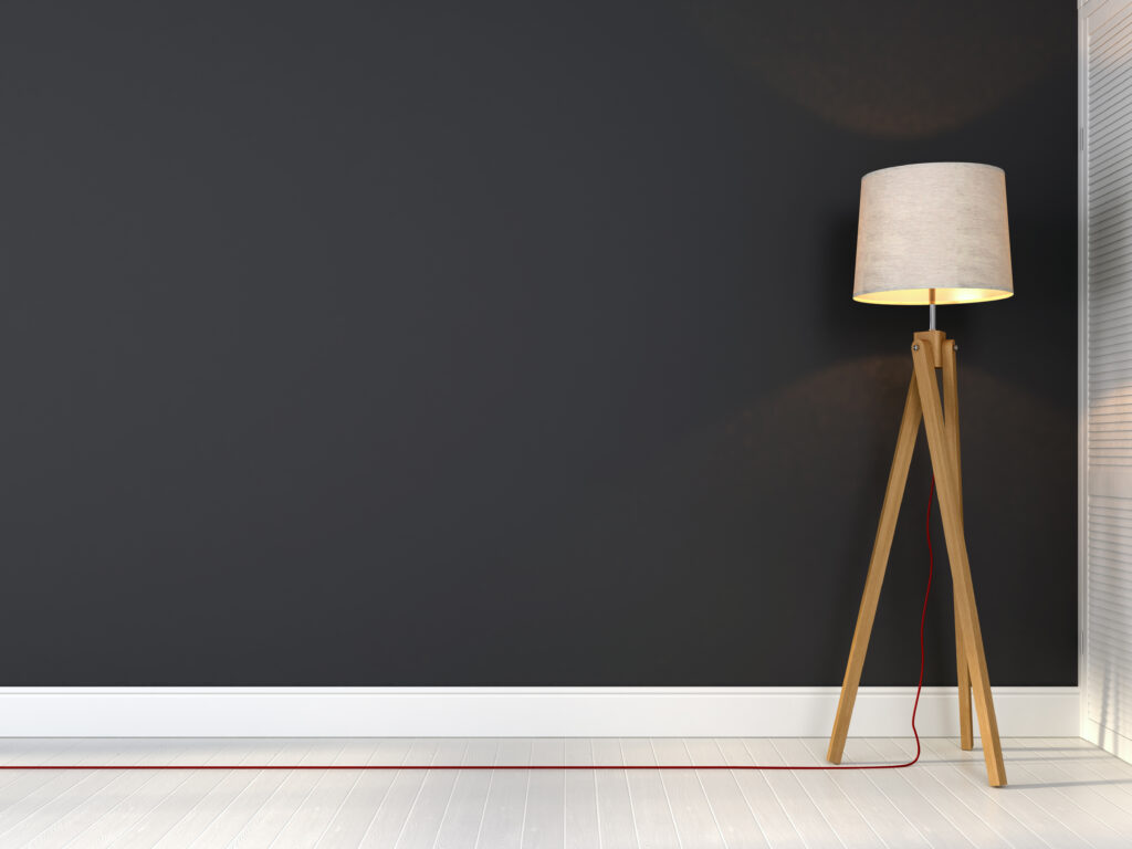 Stylish tripod lamp with red wire on a background of gray wall