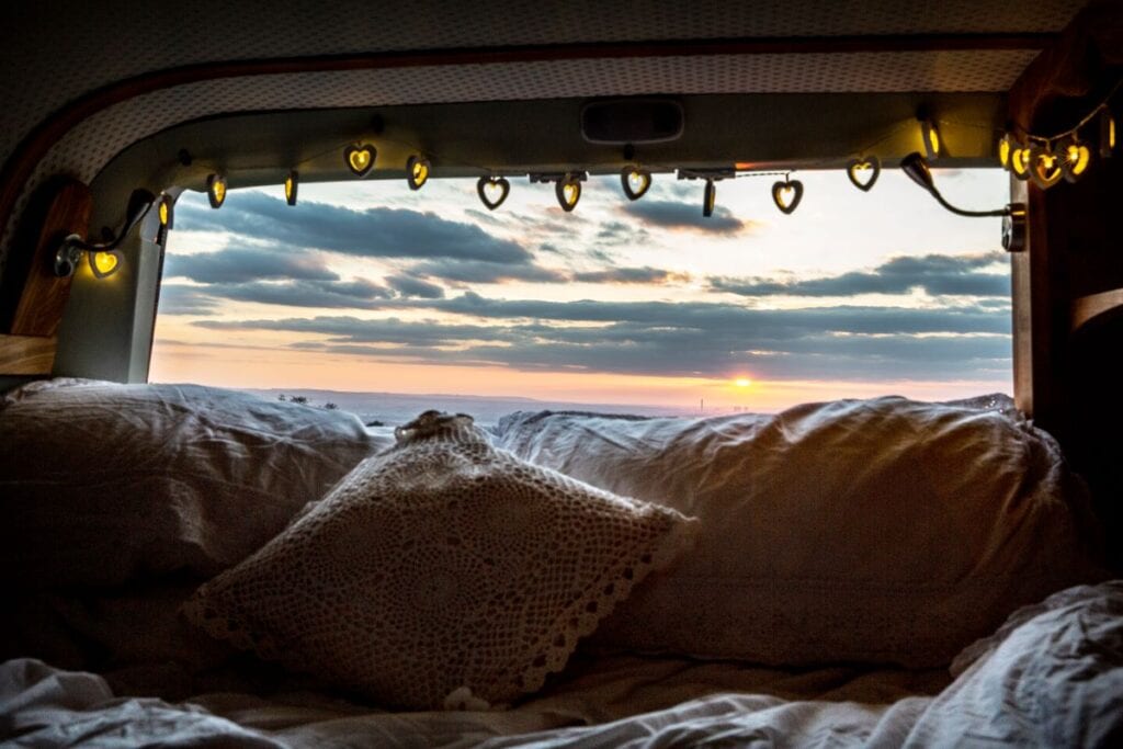 Camper van with boho pillows and string fairy lights, view of sunset