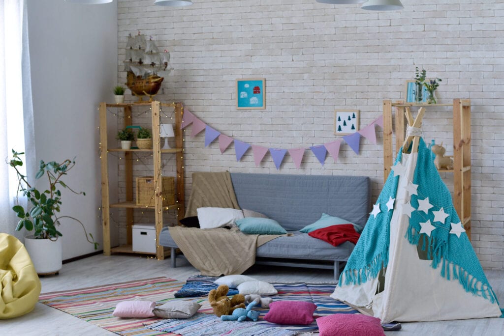 Spacious playroom with teepee tent and abundance of pillows decorates with small flags and lights