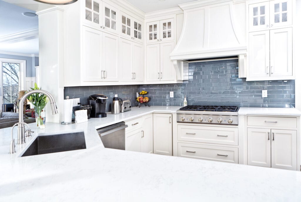 A contemporary home kitchen with stainless steel appliances and painted white cabinets.