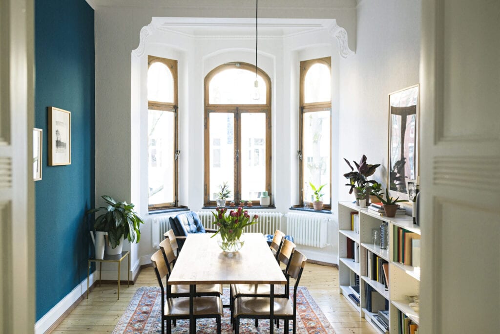 Wooden table and chairs in modern living room with large window front in stylish apartment