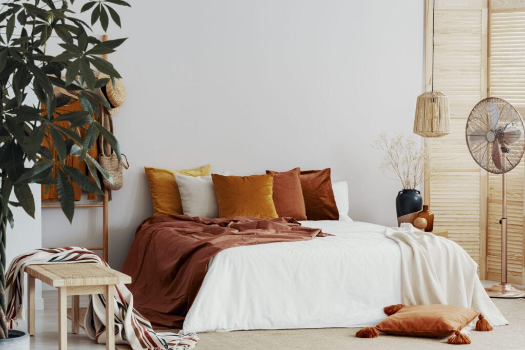 Autumn colored pillows on king size bed in chic bedroom interior