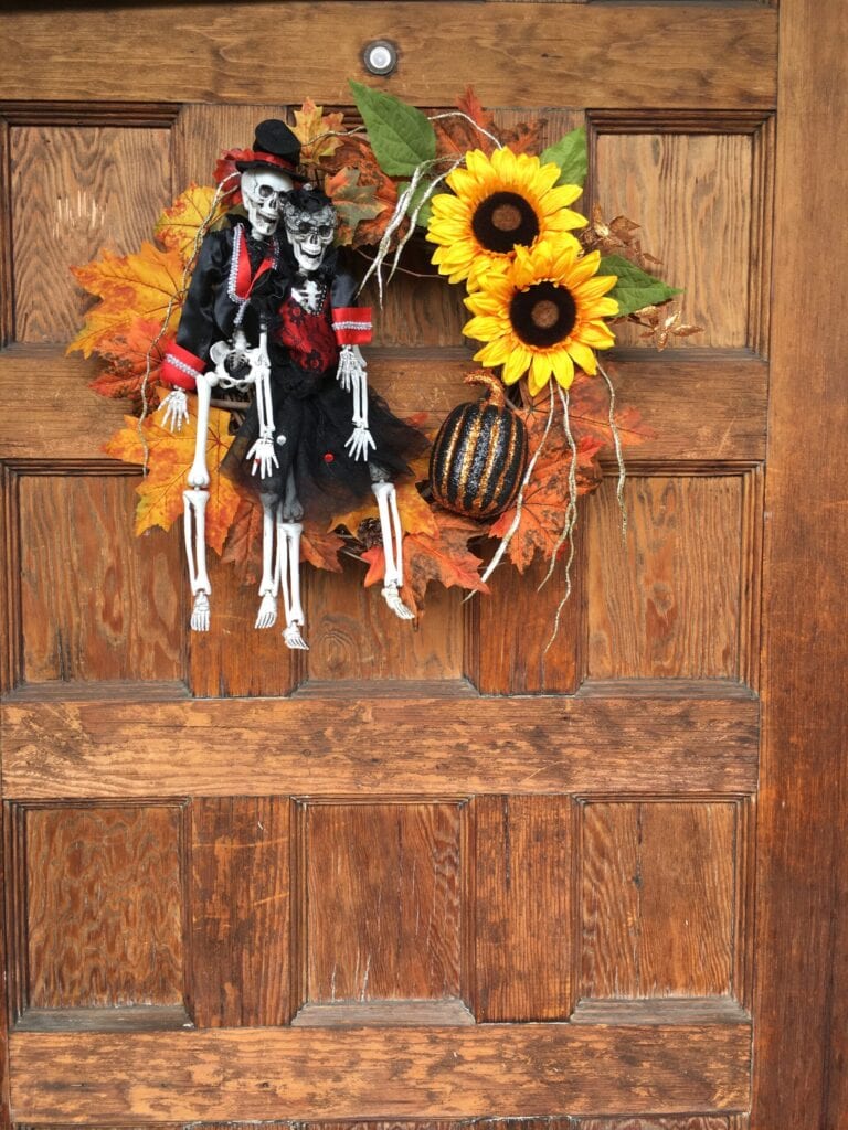 Homemade wreath with Day of the Dead skeletons, fall leaves, sunflowers and pumpkin.