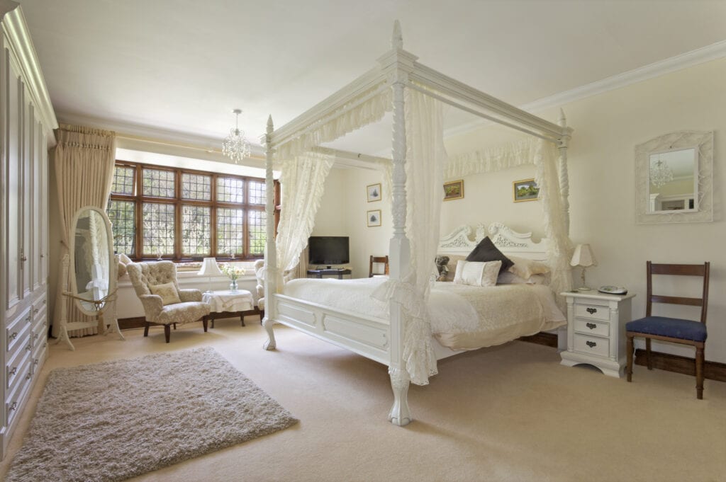 White four-poster bed in a neutral bedroom