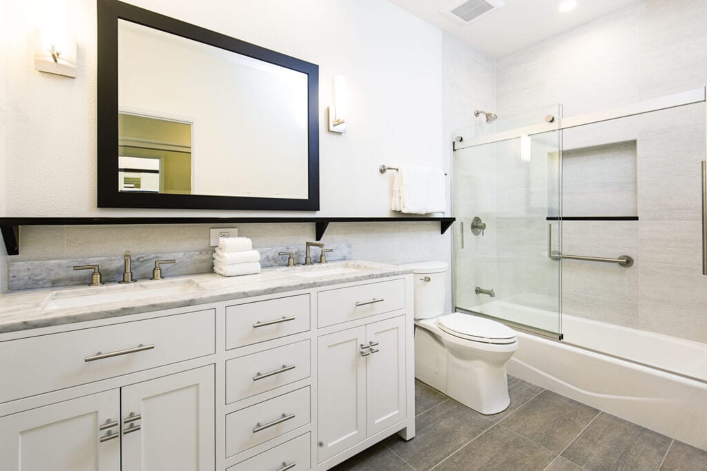 A contemporary modern bathroom design. featuring a bathtub with glass shower stall, toilet and his and her double sink vanity.