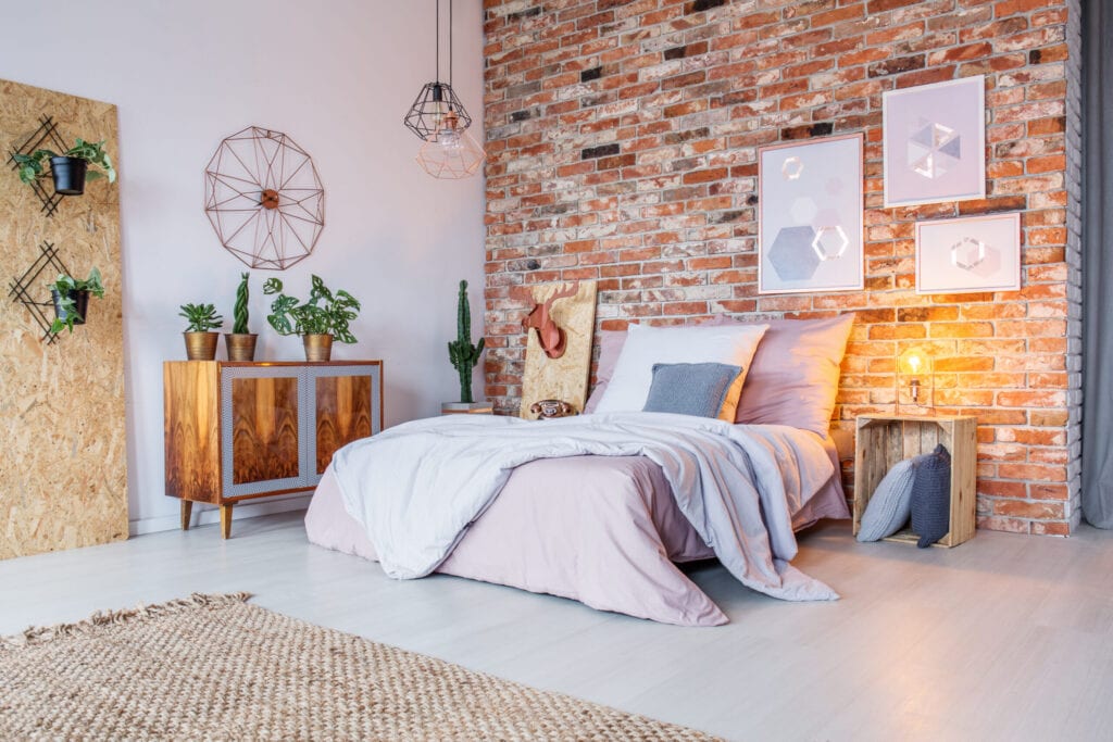 Bright bedroom with double bed, brick wall and rug