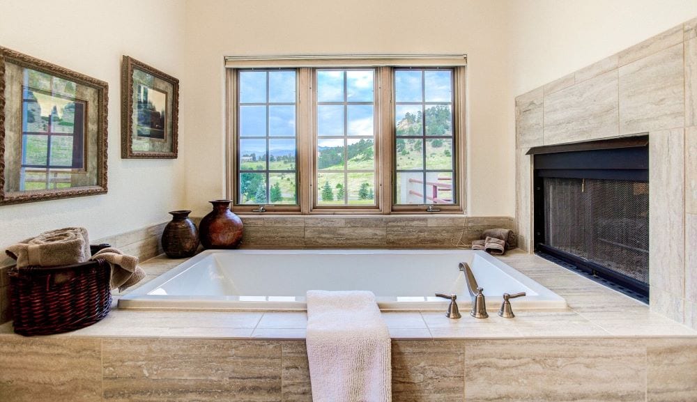 Luxury bathtub with natural light from window and fireplace