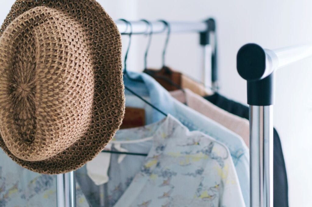 Summer clothes and hat on hanging rack