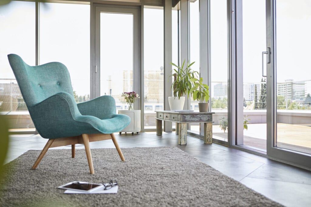 Home interior with armchair, tablet and view on roof terrace