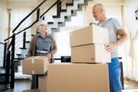 Elderly couple packing boxes, downsizing to smaller home